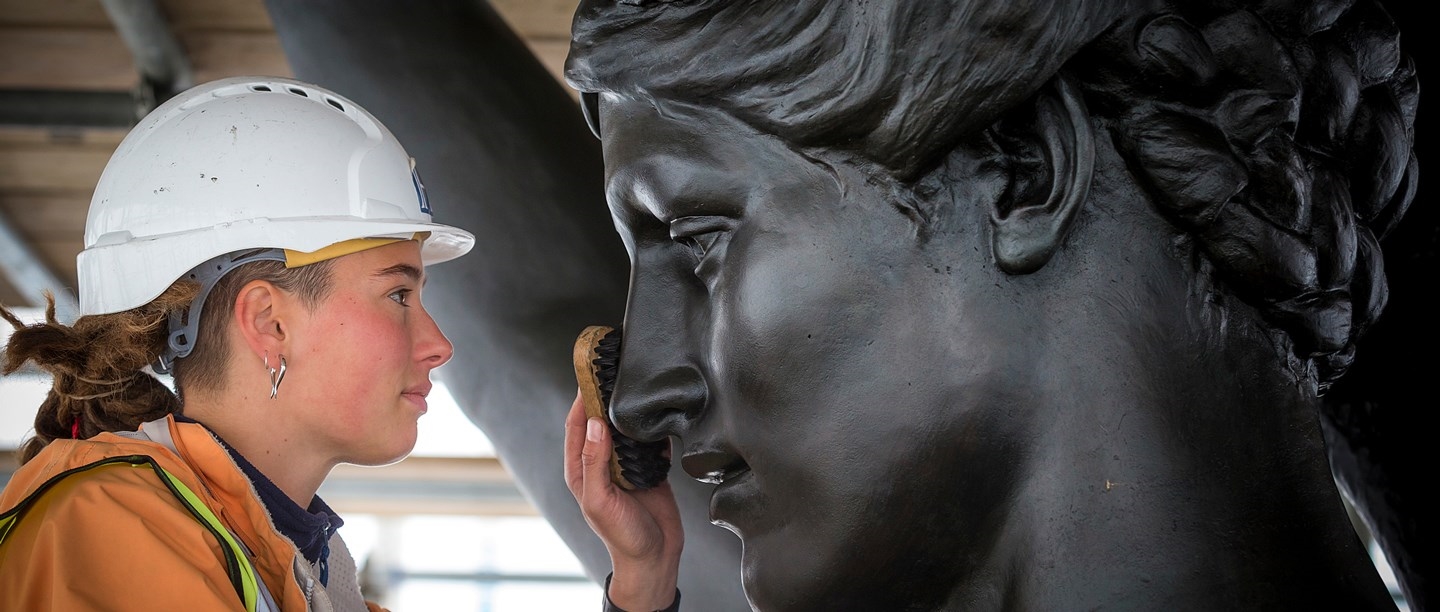A conservator examines some work up close