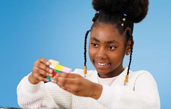 A girl sits playing with Lego bricks