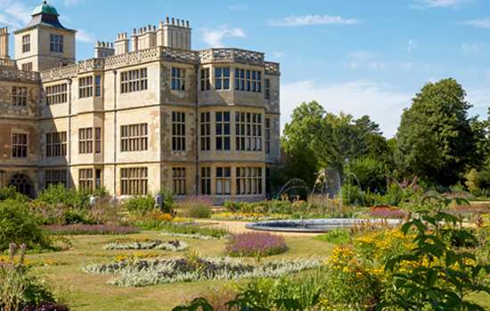 A view of the flower beds with a variety of brightly coloured flowers with Audley End House in the foreground.