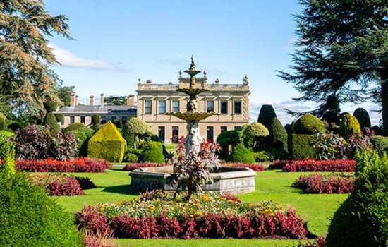 A view of Brodsworth Hall from the gardens filled with colourful flowers.