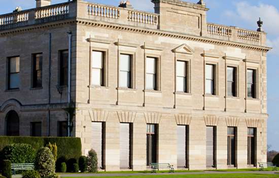 A side on view of Brodsworth Hall underneath a blue sky.