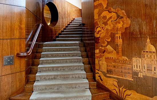 A staircase with lined wooden walls that include a detailed display of some grand buildings