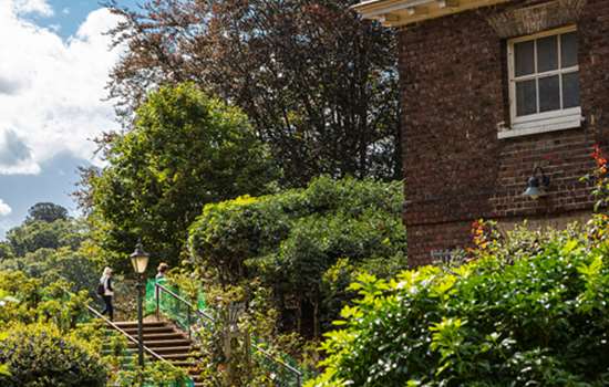 A view of the gardens at Kenwood with a brick building in the foreground.