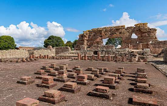 A view of the Roman stone walls and tiles at Wroxeter Roman City on a sunny day.
